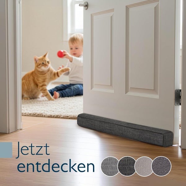 Langer Zugluftstopper aus Stoff vor einer Zimmertür auf Holzboden, im Hintergrund spielen ein Kind und eine Katze.