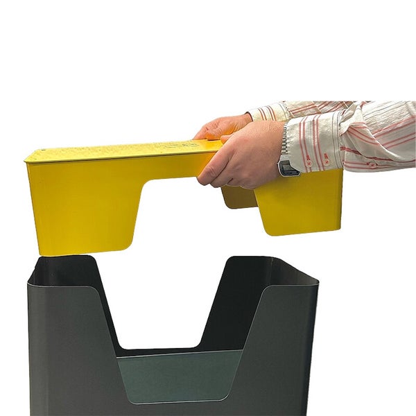 Eine Person setzt einen gelben Einsatz in einen dunklen Briefkasten ein.