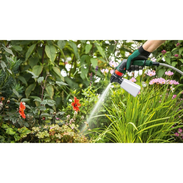 Hand mit Gartenhandschuh hält Sprühgerät zur Pflanzenpflege