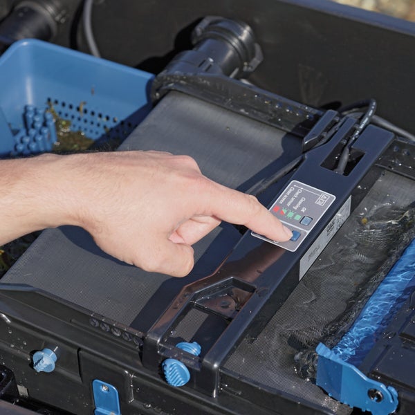 Hand bedient das Kontrollpanel des Teichfilters Oase BioTec ScreenMatic zur Aktivierung der Reinigungsfunktion.