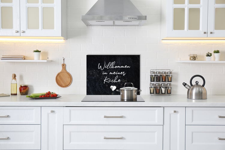 Helle Küche mit Kochfeld, Dunstabzugshaube, Schränken und Deko