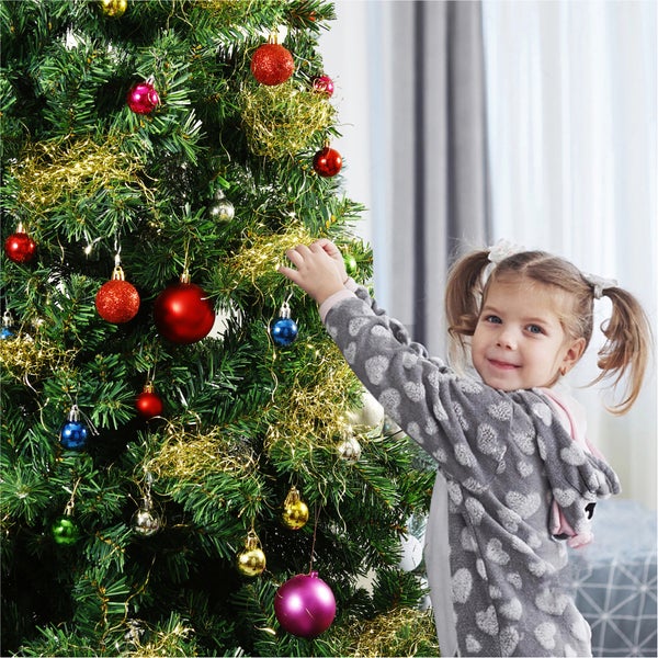 Mädchen schmückt einen Weihnachtsbaum mit Christbaumkugeln und Lametta