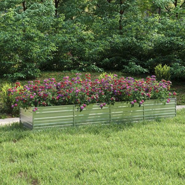 Rechteckiges Hochbeet aus gewelltem Metall mit blühenden Blumen in einem Garten auf einer Rasenfläche.
