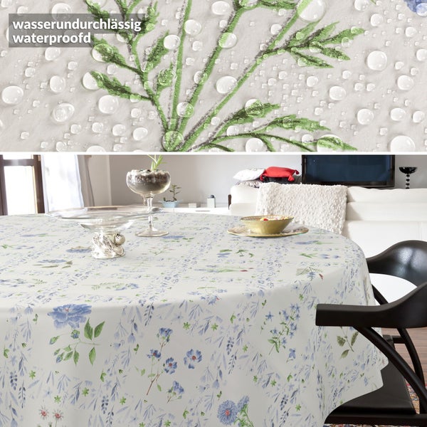 Rundes Tischtuch mit blauem Blumenmuster im Wohnzimmer, Detailansicht zeigt wasserundurchlässige Oberfläche mit Wassertropfen.