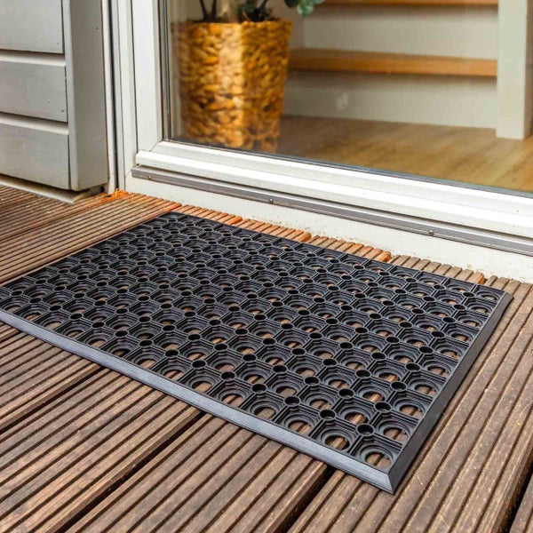 Fußmatte aus Gummi vor einer Tür auf einem Holzdeck