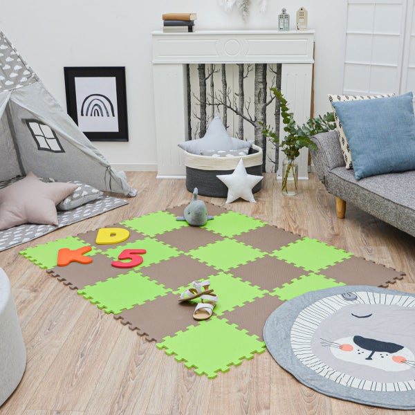 Helles Kinderzimmer mit einer grün-braun karierten Puzzle-Spielmatte auf Holzboden, einem Spielzelt, einem grauen Sofa und einem Kaminsims.