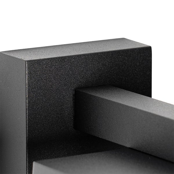 Nahaufnahme einer eckigen Wandhalterung aus schwarz pulverbeschichtetem Metall mit rauer Oberfläche für eine Leuchte.