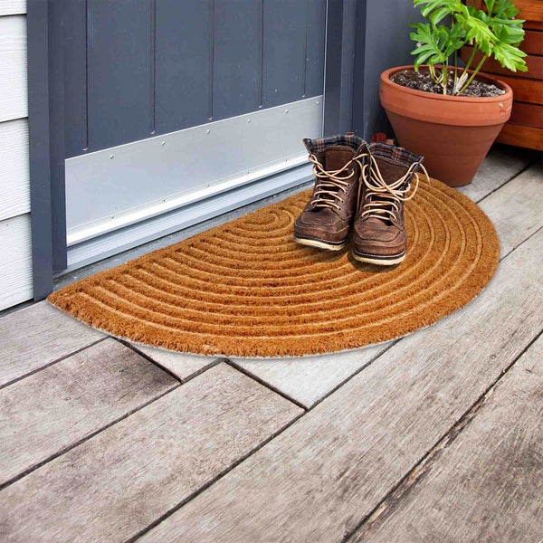 Halbkreisförmige Fußmatte aus Kokosfaser vor einer Tür mit zwei Stiefeln