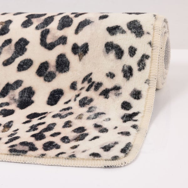 Weicher Teppich mit Leopardenmuster und umkettelten Rändern, teilweise aufgerollt.