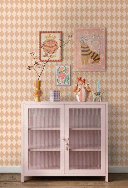 Tapete mit Rautenmuster in Beige und Cremeweiß hinter einem rosa Sideboard mit geriffeltem Glas und bunten Dekorationsartikeln.