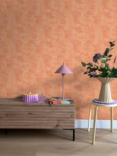 Zimmer mit gemusterter Tapete, Kommode, Lampe und Blumen