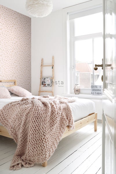 Helles Schlafzimmer mit Holzbett, Strickdecke und Leiterregal