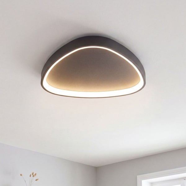 Moderne LED Deckenleuchte in organischer Dreiecksform mit innenliegendem Lichtband an einer Zimmerdecke.