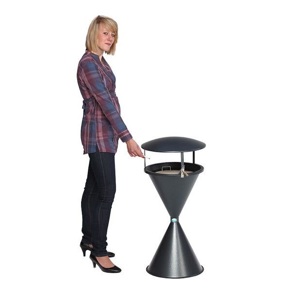 Eine Frau steht neben einem schwarzen Standaschenbecher aus Metall mit Deckel, um die Höhe und Anwendung zu verdeutlichen.