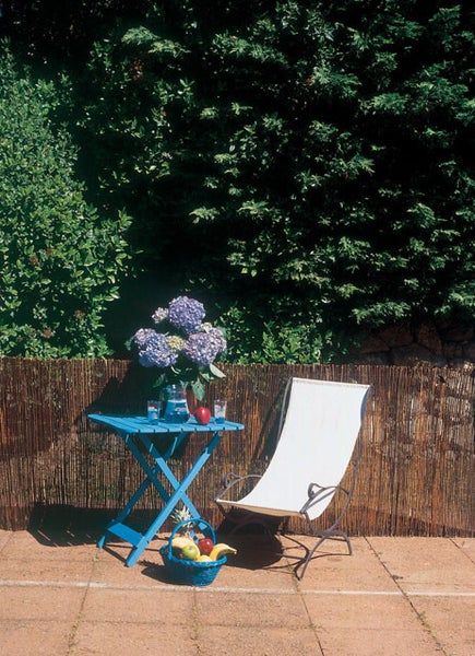 Szene im Freien mit blauem Gartentisch, Gartenstuhl und Flechtzaun