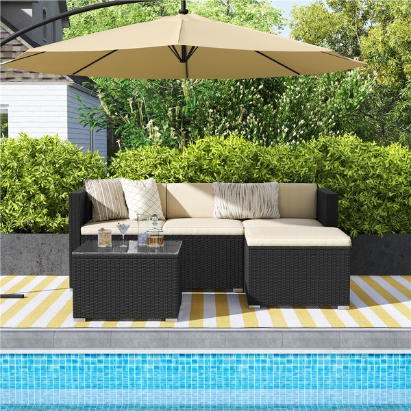 Gartenlounge-Set aus Rattan mit Sonnenschirm auf einer Terrasse am Pool.