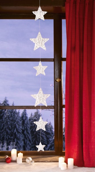 Fensterdekoration mit Sternenlichterkette, Kerzen und rotem Vorhang für weihnachtliche Atmosphäre