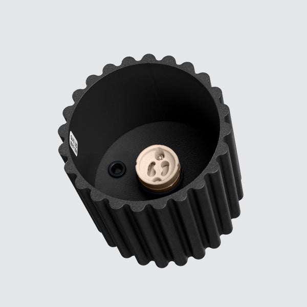 Zylindrische Leuchte mit geriffelter Außenseite und GU10 Fassung.