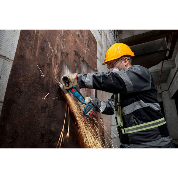 Mann mit Schutzhelm und Schutzbrille benutzt einen Akku-Winkelschleifer an einer Metallplatte.