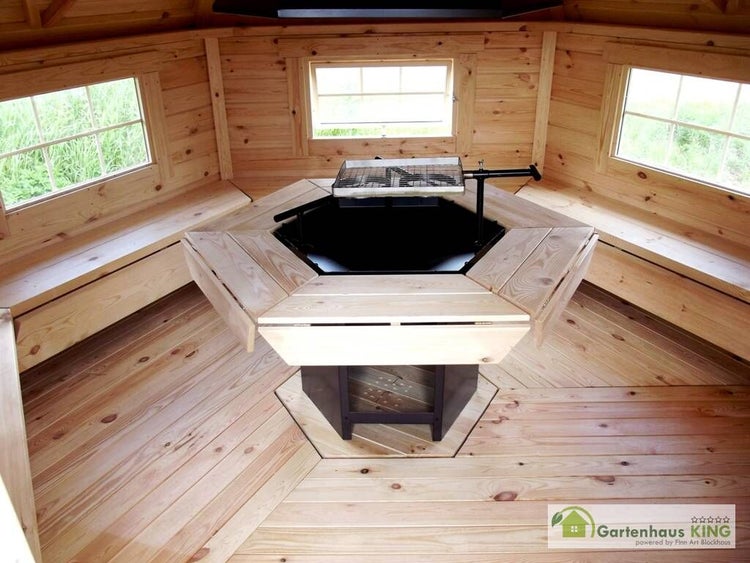 Innenansicht eines Holzgrillhauses mit Grill und Sitzbänken