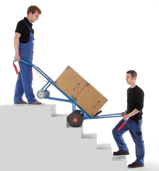 Zwei Arbeiter transportieren mit einer Treppenkarre Kartons auf einer Treppe