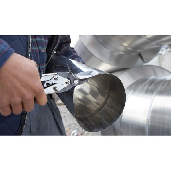 Eine Person schneidet ein Blech mit einer Blechschere.