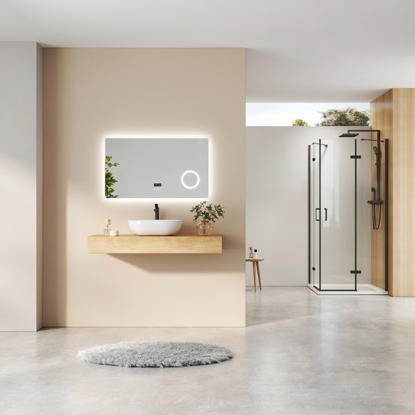 Helles, modernes Badezimmer mit Holzwaschtisch, weißem Aufsatzwaschbecken, beleuchtetem Spiegel und einer Glasduschkabine mit schwarzen Profilen.