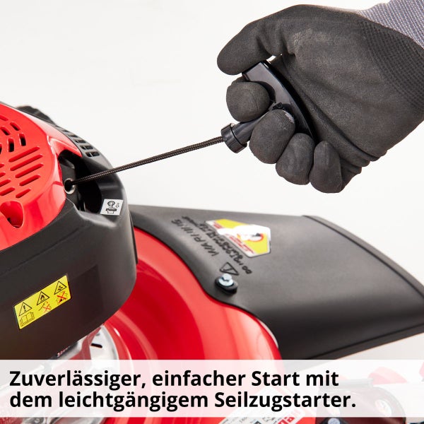 Detailansicht eines Seilzugstarters an einer Gartenmaschine mit einer Hand mit Handschuh, die am Seil zieht