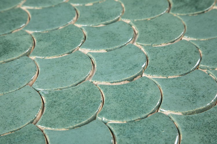 Nahaufnahme von grünlichen Mosaikfliesen in Schuppenform.