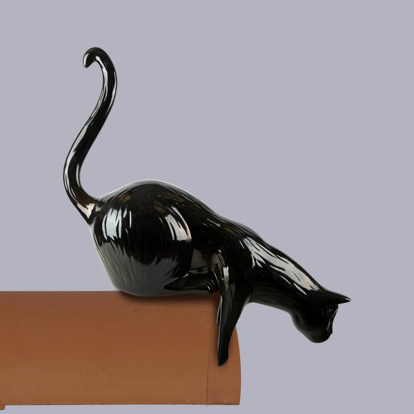 Dachfigur Katze aus Keramik, glasiert, schwarz, kriechend auf einem Dachziegel.