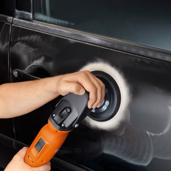 Eine Hand führt eine orangefarbene Poliermaschine zur Fahrzeugpflege über den schwarzen Autolack.