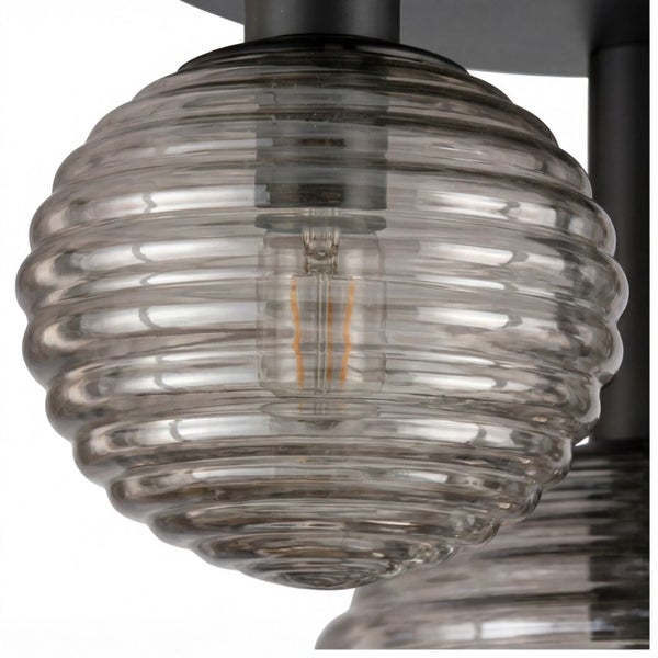 Kugelförmiger Lampenschirm aus geriffeltem Glas mit sichtbarem Leuchtmittel und schwarzer Halterung.