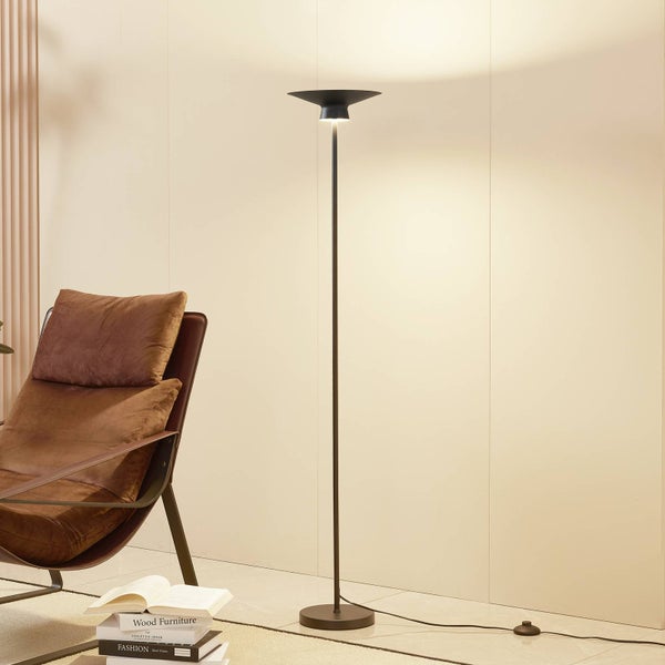 Moderne schwarze Deckenfluter-Stehleuchte mit schlankem Design in einem hellen Wohnzimmer neben einem braunen Ledersessel.