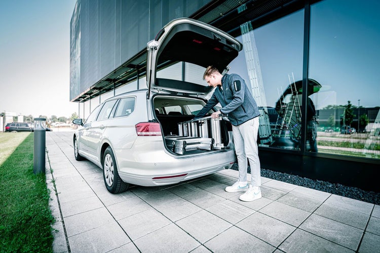 Eine Person verstaut eine Aluminiumleiter in einem Kombi