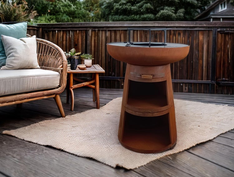 Außenbereichszene mit Feuerstelle aus Metall mit Ablagefächern, Rattansessel und Beistelltisch auf einem Teppich