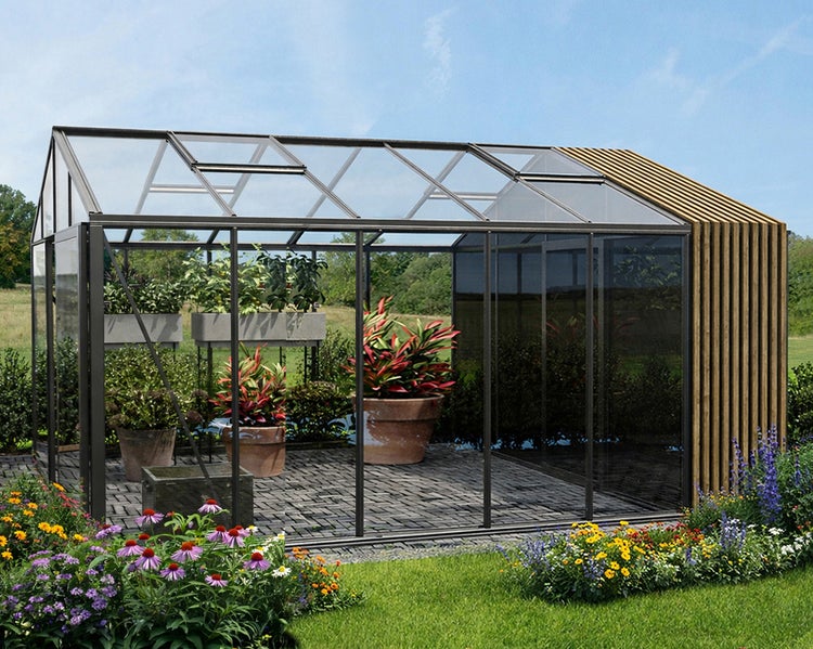Modernes Gewächshaus mit dunklem Metallrahmen, Glaswänden und vertikalen Holzlamellen. Innenraum mit gepflastertem Boden und Pflanzen im Garten.
