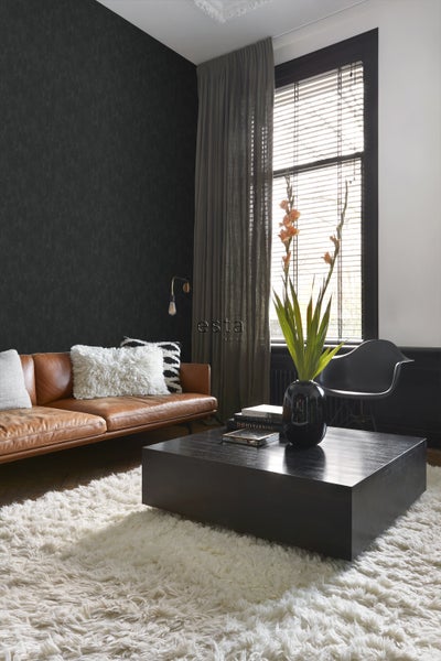 Wohnzimmer mit braunem Ledersofa, dunkler Wand und schwarzem Couchtisch auf einem Teppich