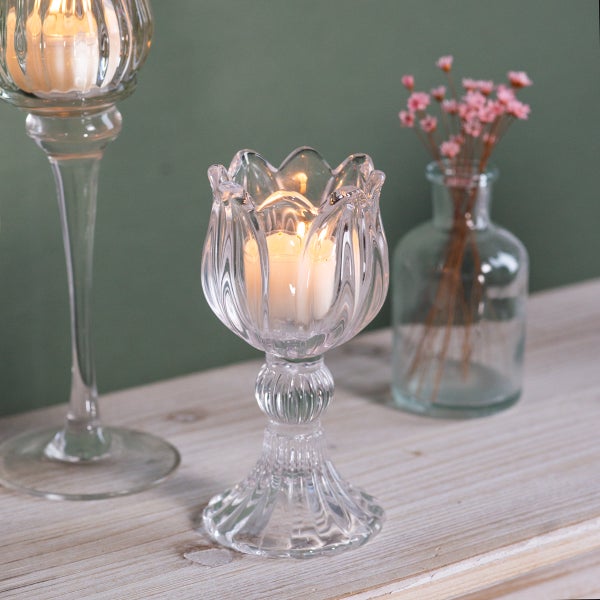 Tulpenförmiger Teelichthalter aus klarem Glas mit geriffelter Struktur und brennender Kerze auf einer Holzoberfläche.