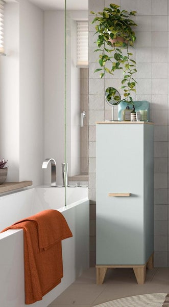 Moderner Badezimmerschrank mit Holzfüßen und passendem Griff neben einer weißen Badewanne mit Duschwand und orangefarbenem Handtuch im Badezimmer.