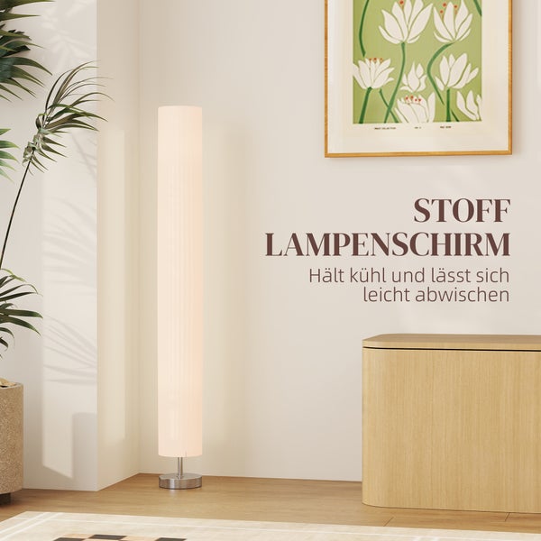 Moderne Stehlampe mit hohem zylindrischem Stofflampenschirm in einem hellen Raum neben einem Holzmöbel.