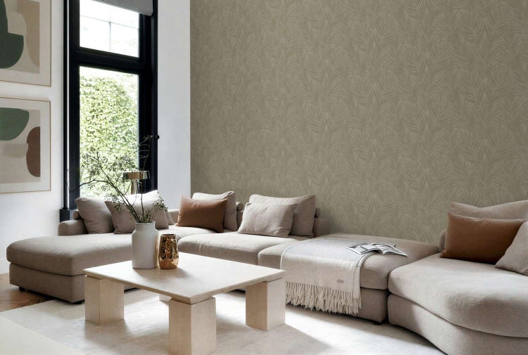 Wohnzimmer mit beiger Vliestapete mit Blattmuster, großem Sofa, Holztisch und Dekoration in einem hellen, modernen Wohnraum.