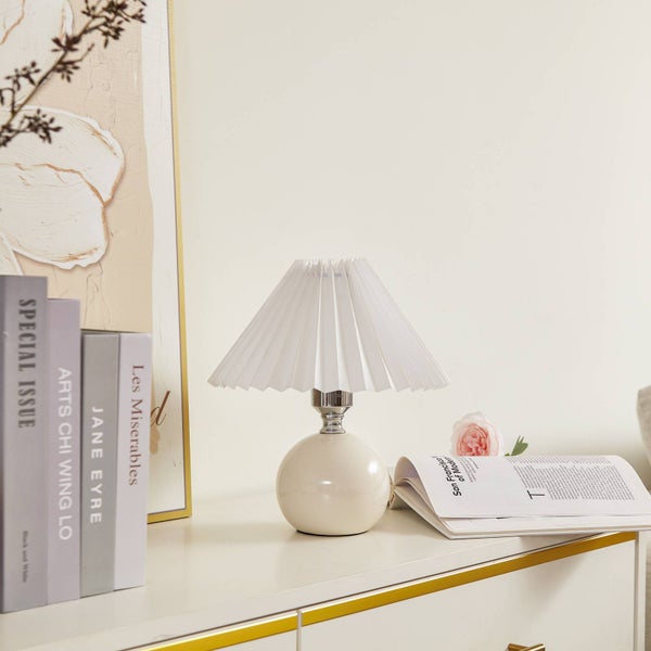 Dekorative Tischleuchte mit weißem Lampenschirm und Büchern auf einem Tisch