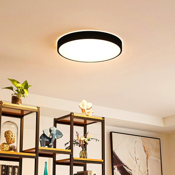 Runde LED-Deckenleuchte mit schwarzem Gehäuse und weißer Abdeckung an einer Decke in einem modern eingerichteten Wohnbereich.