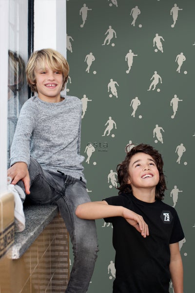 Zwei Jungen vor einer grünen Tapete mit Fußballspieler-Motiv