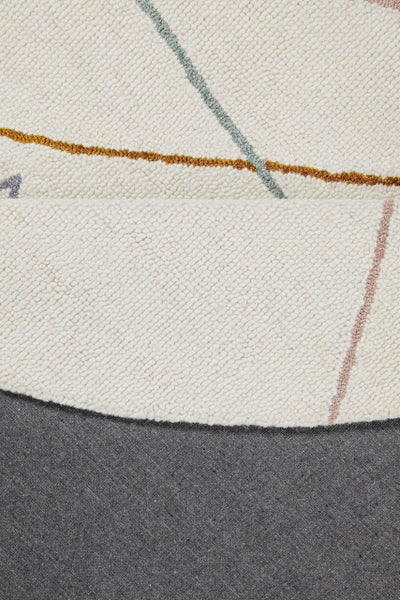 Detailansicht eines hellen getufteten Teppichs mit Schlingenflor, bunten geometrischen Linien und grauer Textilrückseite.