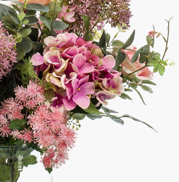 Künstlicher Blumenstrauß mit rosafarbener Hortensie, Rosen und grünen Blättern in einer Glasvase.