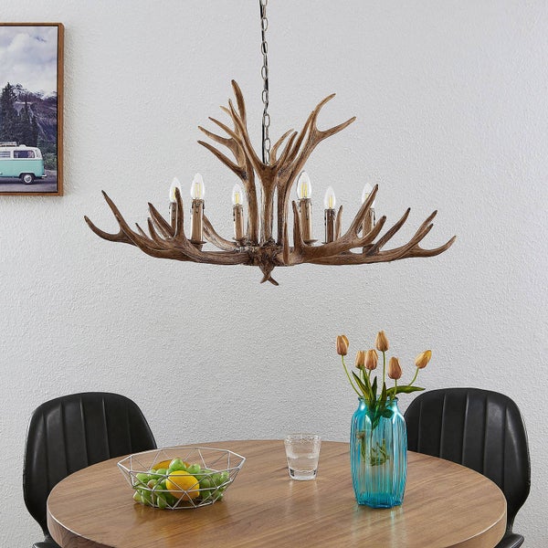 Kronleuchter im Geweih Design über einem Holztisch mit Obstschale und Blumenvase