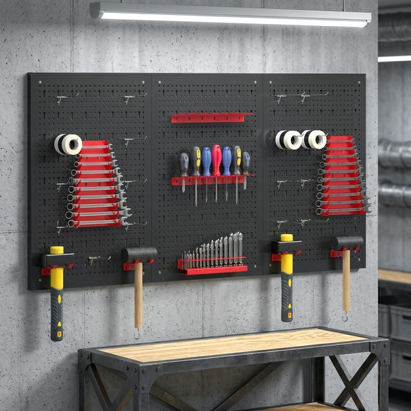 Organisierte Werkstatt mit schwarzer Lochwand an einer Betonwand, bestückt mit Werkzeugen wie Hämmern und Schlüsseln, über einer hölzernen Werkbank.