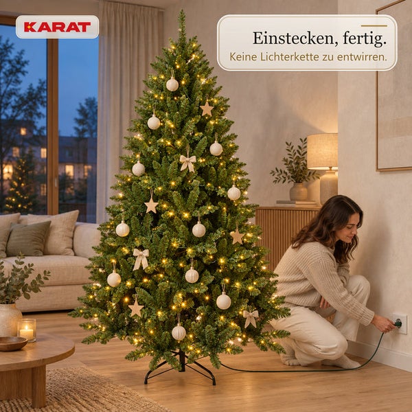 Künstlicher Weihnachtsbaum von Karat mit integrierter LED Beleuchtung in einem Wohnzimmer, eine Frau schließt den Stecker an die Steckdose an.