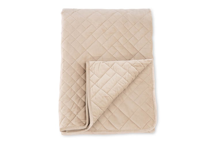 Gefaltete beige gesteppte Tagesdecke mit Rautenmuster und weicher Textur.